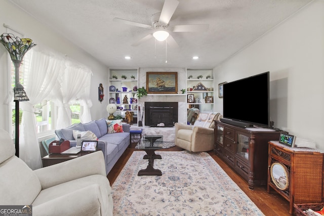 living room featuring recessed lighting, dark wood finished floors, a fireplace, built in features, and ceiling fan