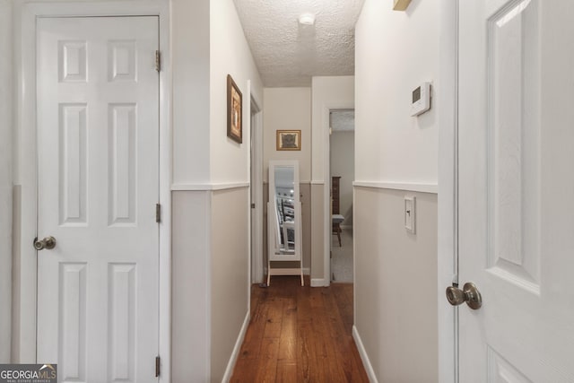 hall with baseboards, dark wood-style flooring, and a textured ceiling
