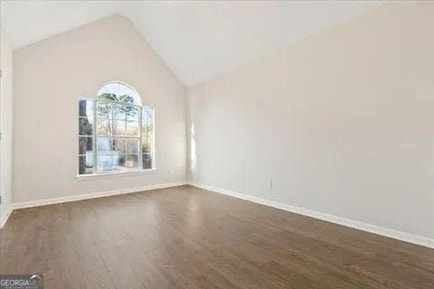 2317 Rocksram Ct, Buford, GA 30519 - unfurnished room with baseboards, vaulted ceiling, and dark wood-type flooring