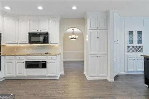 2317 Rocksram Ct, Buford, GA 30519 - kitchen featuring white cabinets, a notable chandelier, arched walkways, decorative backsplash, and black appliances