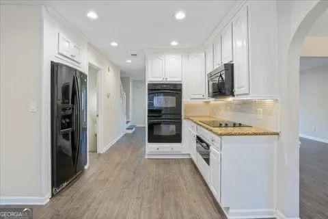 2317 Rocksram Ct, Buford, GA 30519 - kitchen featuring arched walkways, recessed lighting, baseboards, white cabinetry, and black appliances