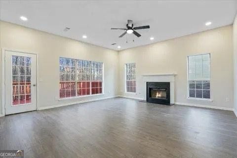 2317 Rocksram Ct, Buford, GA 30519 - unfurnished living room featuring plenty of natural light, a fireplace with flush hearth, ceiling fan, and wood finished floors