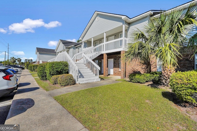 108 Magnolia Plantation Trce Unit 108, Hinesville, GA 31313 - coastal home featuring brick siding, covered porch, stairway, and a front yard
