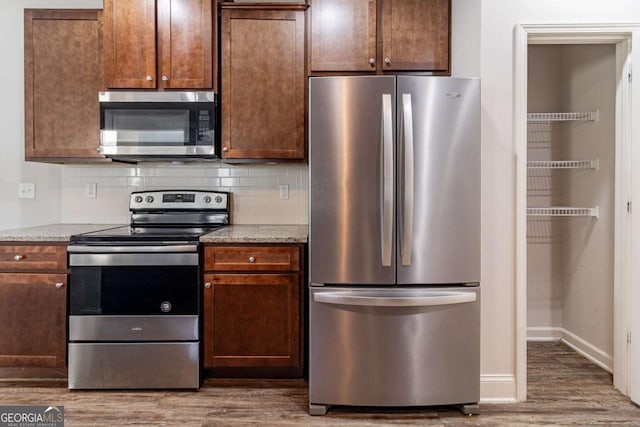 440 Dublin Way, Dallas, GA 30132 - kitchen with stainless steel appliances, wood finished floors, light stone countertops, baseboards, and tasteful backsplash