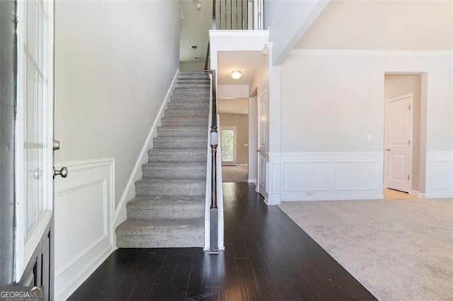 2212 Reddy Farm Ln, Grayson, GA 30017 - staircase featuring wainscoting, a towering ceiling, a decorative wall, hardwood / wood-style flooring, and ornamental molding