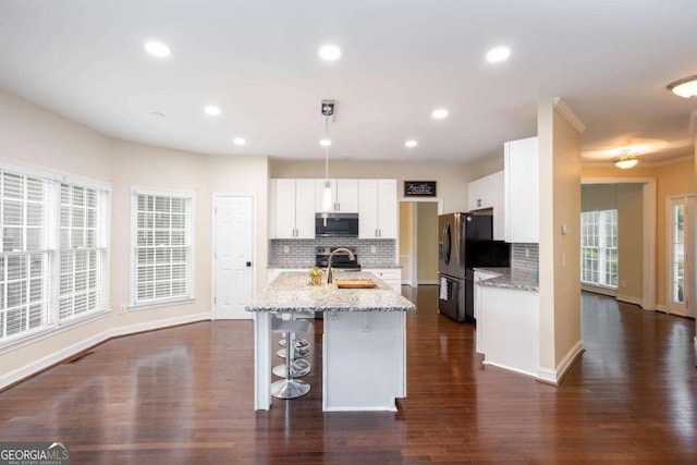 1533 Fallen Leaf Dr SW, Marietta, GA 30064 - kitchen featuring tasteful backsplash, an island with sink, a breakfast bar area, stainless steel appliances, and white cabinetry
