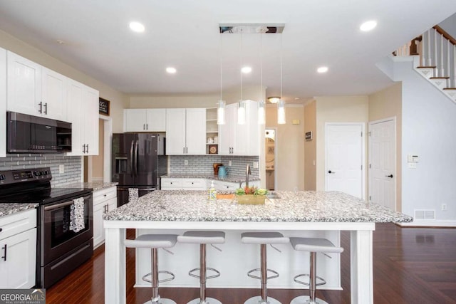 1533 Fallen Leaf Dr SW, Marietta, GA 30064 - kitchen with stainless steel range with electric cooktop, black refrigerator with ice dispenser, visible vents, and tasteful backsplash