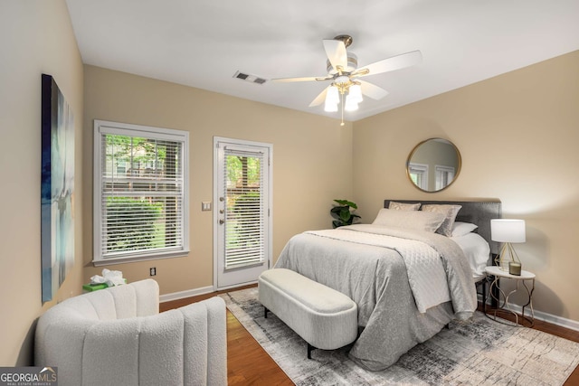 bedroom featuring wood finished floors, access to outside, ceiling fan, baseboards, and visible vents