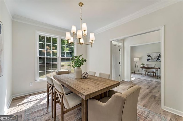 dining space featuring wood finished floors, baseboards, a chandelier, and ornamental molding