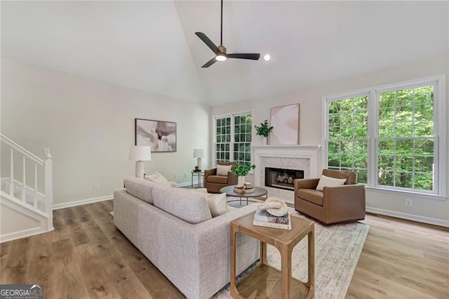 living room with a fireplace, wood finished floors, a healthy amount of sunlight, and a ceiling fan
