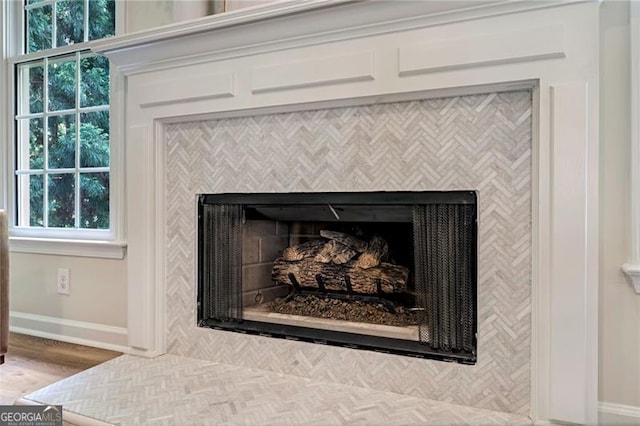 interior details with wood finished floors, a tile fireplace, and baseboards