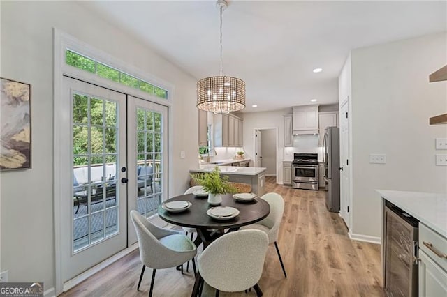 dining room with a chandelier, light wood finished floors, french doors, and wine cooler