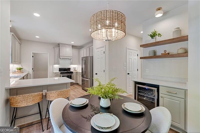 dining space with recessed lighting, light wood-style floors, beverage cooler, and an inviting chandelier