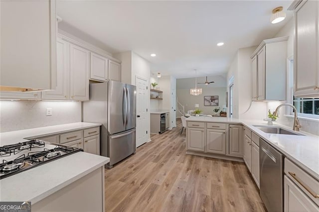 kitchen with recessed lighting, light countertops, a sink, light wood-style floors, and appliances with stainless steel finishes
