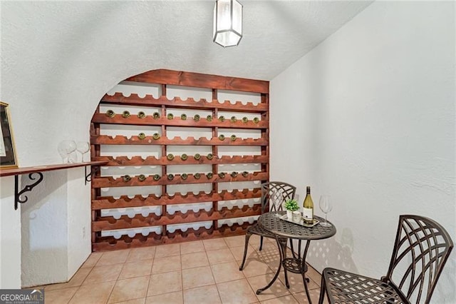 wine area with a textured wall and tile patterned floors