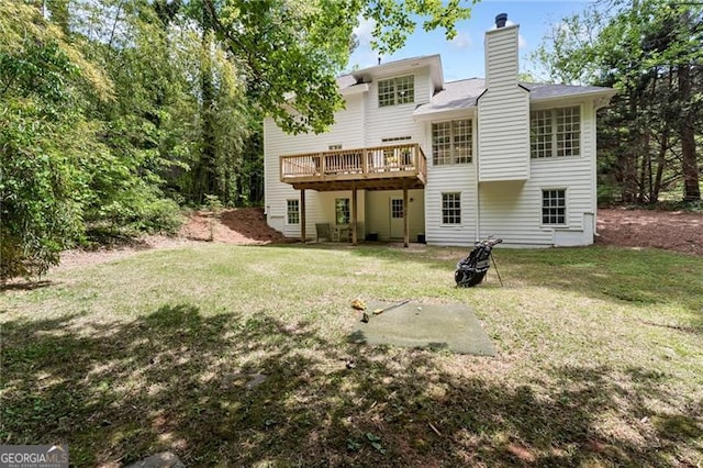 back of house featuring a chimney, a yard, and a deck