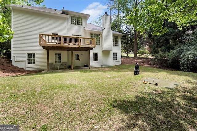 rear view of property featuring a chimney, a yard, and a deck