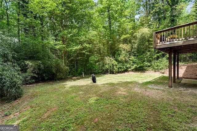 view of yard featuring a wooden deck and a wooded view
