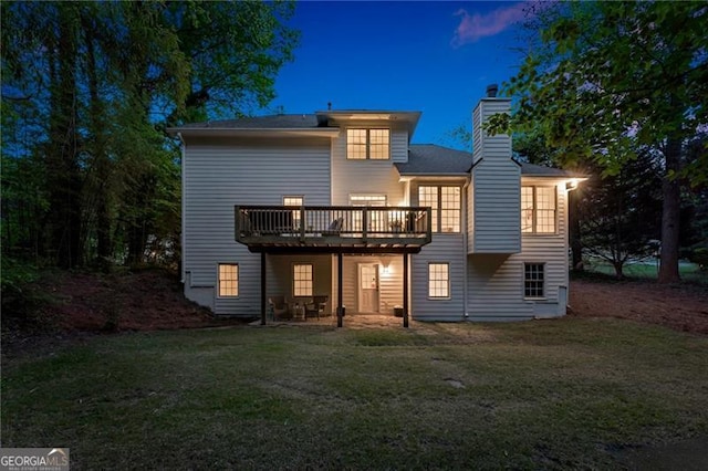 back of property with a lawn, a chimney, and a deck