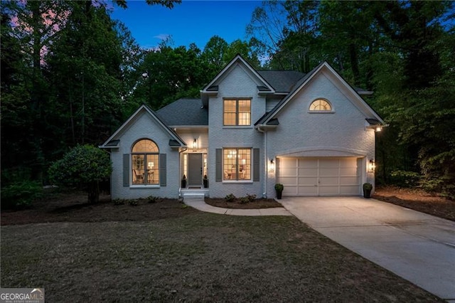 traditional-style home with driveway, brick siding, and a garage