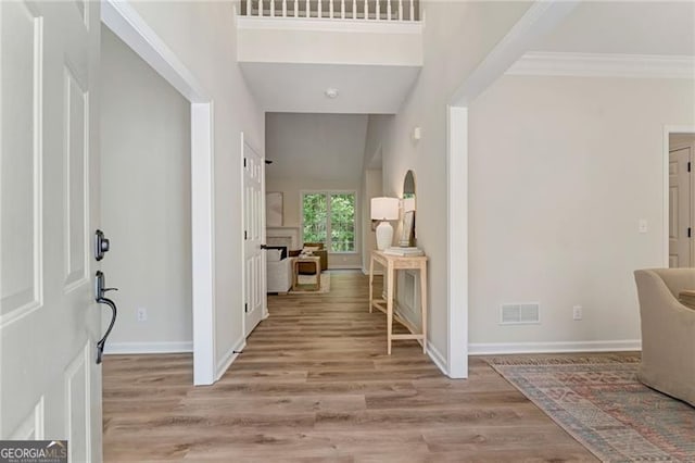 foyer entrance featuring wood finished floors, visible vents, crown molding, and baseboards