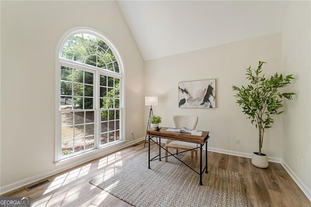 home office featuring high vaulted ceiling, baseboards, wood finished floors, and visible vents