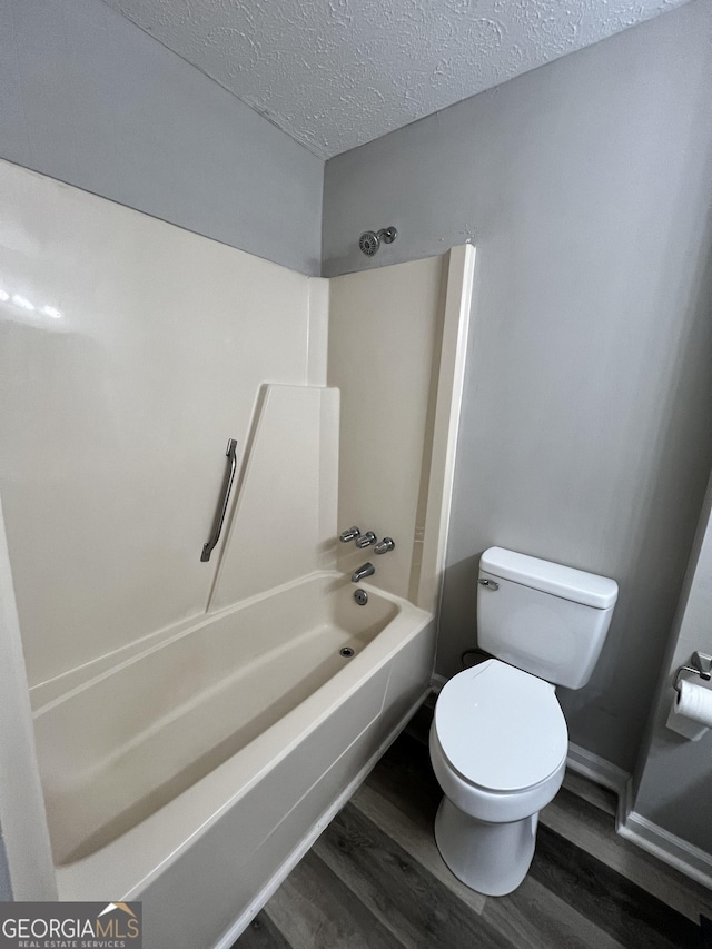 2045 Greentree Pkwy, Macon, GA 31220 - bathroom featuring a textured ceiling, baseboards, toilet, shower / bathing tub combination, and wood finished floors