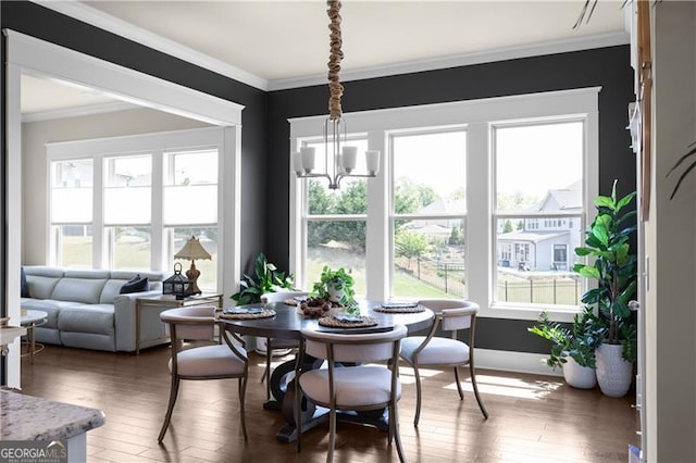 dining area with baseboards, crown molding, hardwood / wood-style flooring, and an inviting chandelier