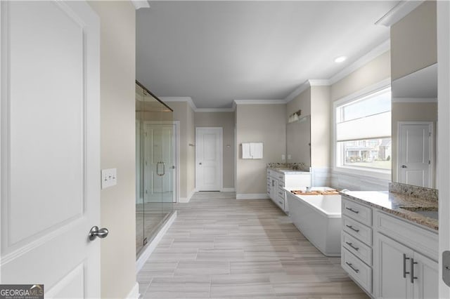 bathroom featuring a washtub, a stall shower, baseboards, ornamental molding, and two vanities