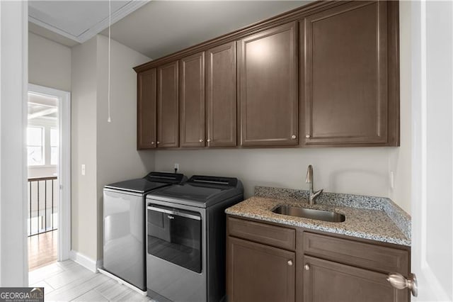 laundry room featuring a sink, washing machine and dryer, baseboards, cabinet space, and attic access