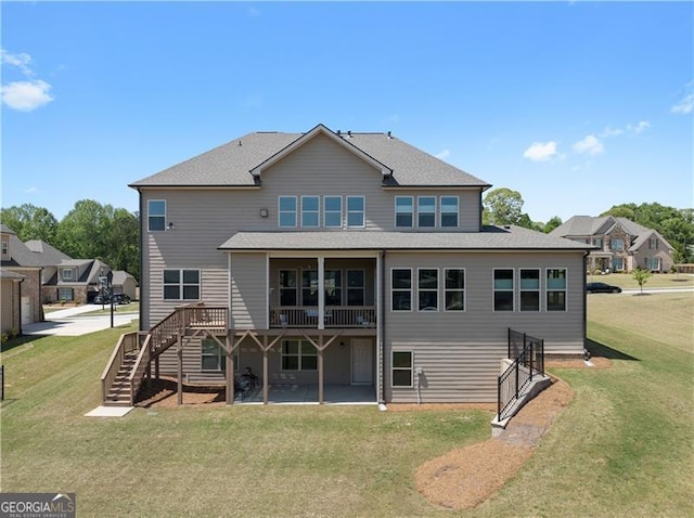 rear view of property featuring a wooden deck, a yard, stairs, and a patio