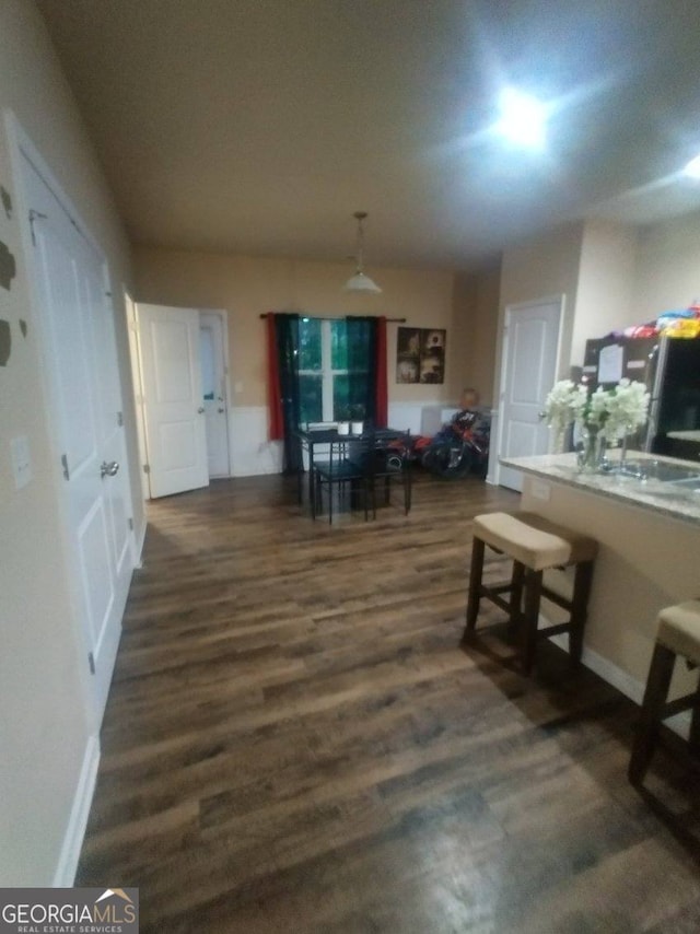 dining space featuring dark wood-type flooring and baseboards