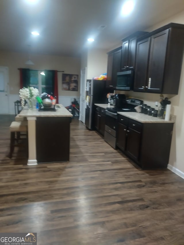 kitchen featuring light countertops, appliances with stainless steel finishes, a center island, and dark wood finished floors