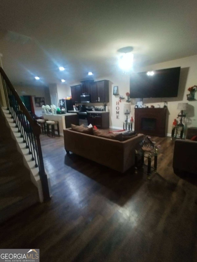 living area with recessed lighting, dark wood finished floors, a fireplace, and stairway
