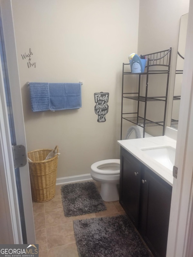 half bath with vanity, baseboards, tile patterned floors, and toilet