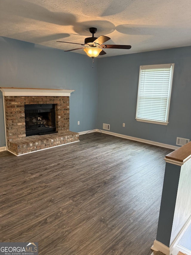4616 Hamlet Walk SE, Conyers, GA 30094 - unfurnished living room with dark wood-type flooring, a ceiling fan, baseboards, a textured ceiling, and a brick fireplace