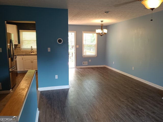 4616 Hamlet Walk SE, Conyers, GA 30094 - unfurnished living room with a chandelier, a sink, baseboards, dark wood finished floors, and a textured ceiling