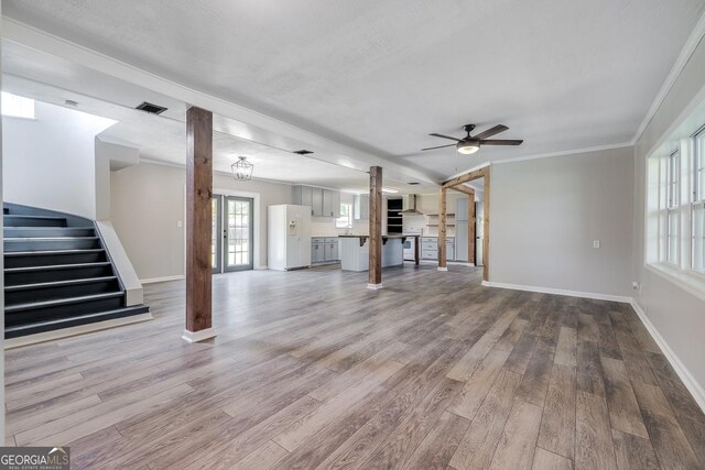 203 N Lake Dr, Brunswick, GA 31525 - unfurnished living room featuring decorative columns, baseboards, a ceiling fan, wood finished floors, and stairs