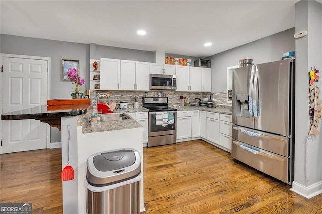 3682 Brantley Ave, Brunswick, GA 31520 - kitchen featuring a sink, a breakfast bar, white cabinetry, a peninsula, and appliances with stainless steel finishes