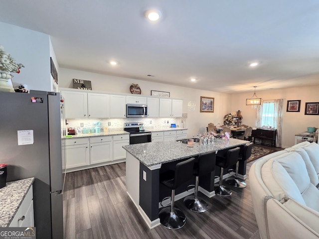 288 Mccall Way, Monroe, GA 30655 - kitchen featuring stainless steel appliances, a kitchen breakfast bar, dark wood-style floors, open floor plan, and light stone countertops
