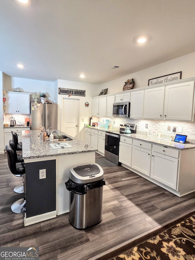288 Mccall Way, Monroe, GA 30655 - kitchen featuring stainless steel appliances, a sink, dark wood-style flooring, white cabinetry, and a breakfast bar