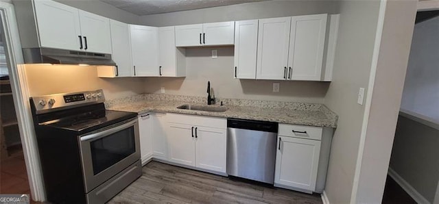185 Johnson Dr, Athens, GA 30605 - kitchen featuring appliances with stainless steel finishes, under cabinet range hood, white cabinets, light stone countertops, and dark wood finished floors