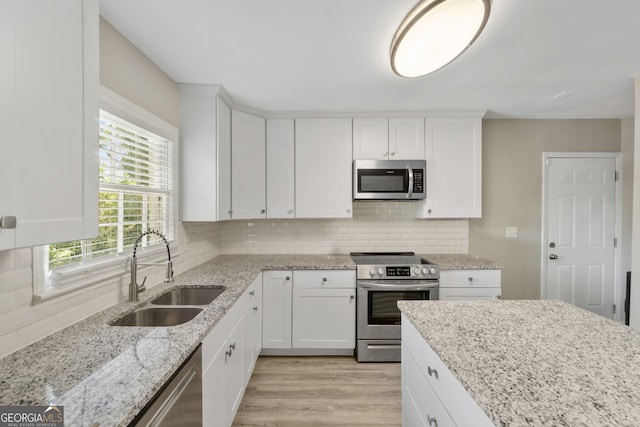 1825 SW Willis Mill Rd, Atlanta, GA 30311 - kitchen with a sink, decorative backsplash, light wood-style flooring, white cabinets, and appliances with stainless steel finishes