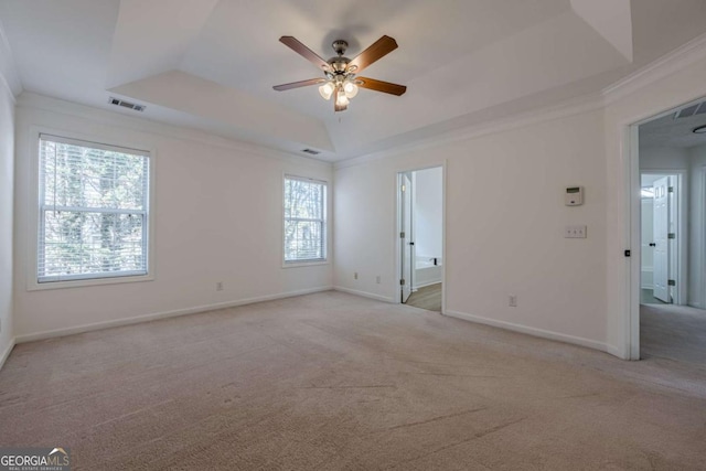 unfurnished room featuring visible vents, a tray ceiling, and light colored carpet