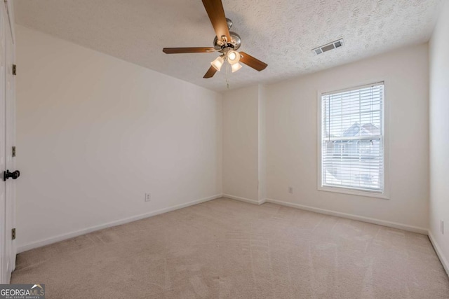 spare room with carpet floors, visible vents, a ceiling fan, and baseboards
