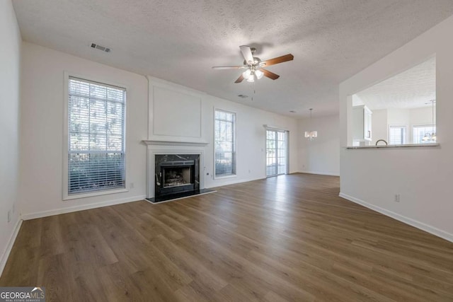 unfurnished living room with baseboards, a ceiling fan, wood finished floors, and a textured ceiling