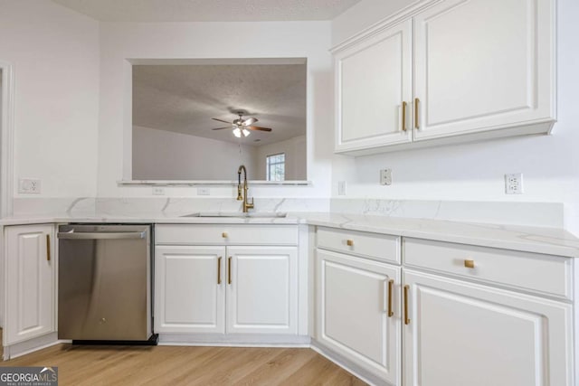 kitchen with stainless steel dishwasher, a ceiling fan, a sink, light wood-style flooring, and white cabinets