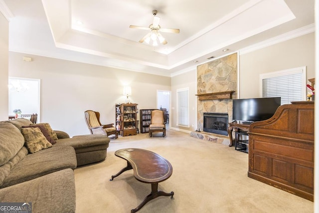 living area featuring a ceiling fan, carpet, a fireplace, ornamental molding, and a raised ceiling