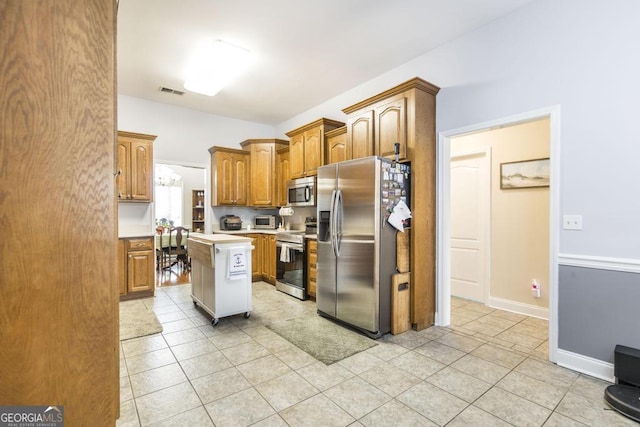 kitchen with light tile patterned flooring, visible vents, light countertops, a kitchen island, and appliances with stainless steel finishes