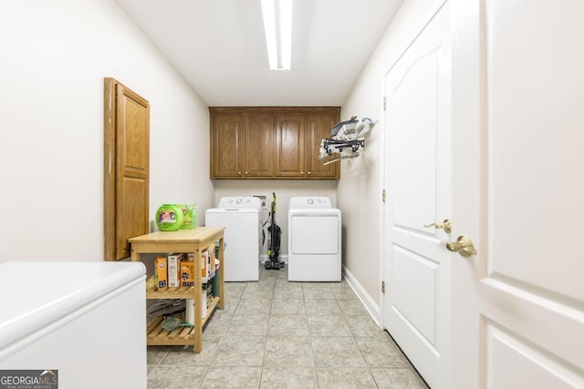 laundry room with washing machine and clothes dryer, light tile patterned flooring, and cabinet space